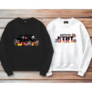 May include: Two black and white sweatshirts with a Mickey Mouse theme. The black sweatshirt has the text "Birthday Boy" with Mickey Mouse characters forming the letters. The white sweatshirt has the text "Birthday Girl" with Mickey Mouse characters forming the letters.