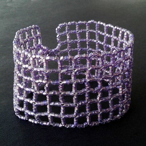 May include: A purple beaded bracelet with a woven, grid-like design.