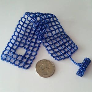 May include: A blue beaded bracelet with a grid pattern. The bracelet is about the size of a quarter.