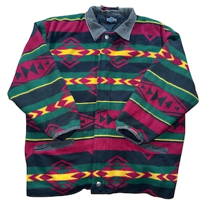 May include: A colorful fleece jacket with a geometric pattern in shades of red, green, yellow, and black. The jacket has a corduroy collar and two front pockets. The jacket is buttoned up.