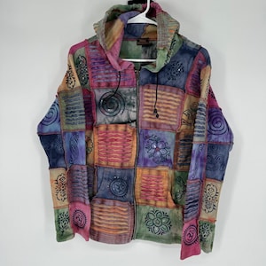 May include: A patchwork zip-up hoodie in a variety of colors, including pink, blue, green, and orange. The jacket features a hood with a drawstring and is decorated with embroidered floral and geometric patterns. The jacket is hanging on a white hanger.