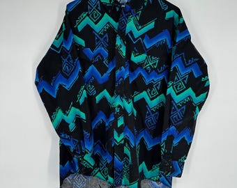 May include: Black button-down shirt with a vibrant geometric pattern in shades of blue and teal. The long-sleeved shirt features a classic collar and two chest pockets, perfect for casual wear.
