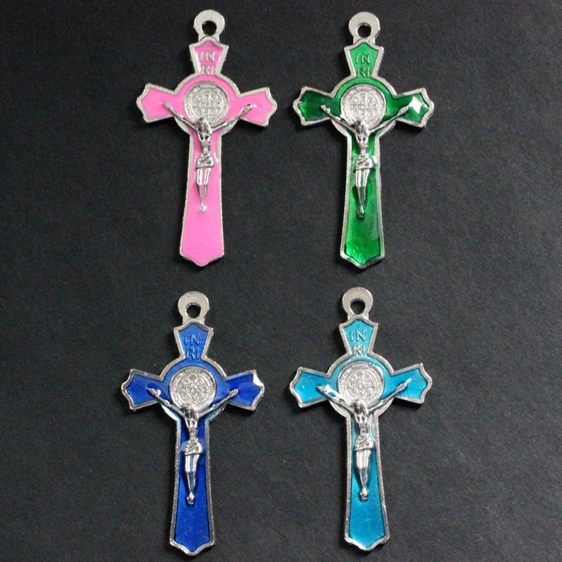 Puede incluir: Cuatro crucifijos de metal plateado con una figura plateada de Jesucristo en la cruz. Cada crucifijo tiene una medalla redonda de plata con un dise&ntilde;o en el centro. Los crucifijos est&aacute;n pintados en cuatro colores diferentes: rosa, verde, azul y azul claro.