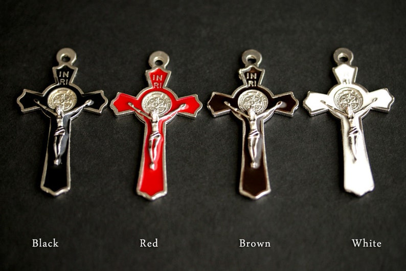 Puede incluir: Cuatro crucifijos de metal con una medalla de San Benito en el centro. Los crucifijos son negros, rojos, marrones y blancos.