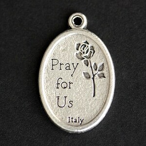 May include: Silver oval charm with a rose and the words "Pray for Us" and "Italy" engraved on it.