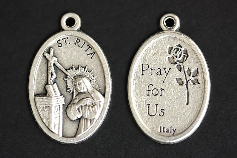 May include: Silver oval pendant with a depiction of Saint Rita of Cascia on one side and the words "Pray for Us Italy" and a rose on the other side.