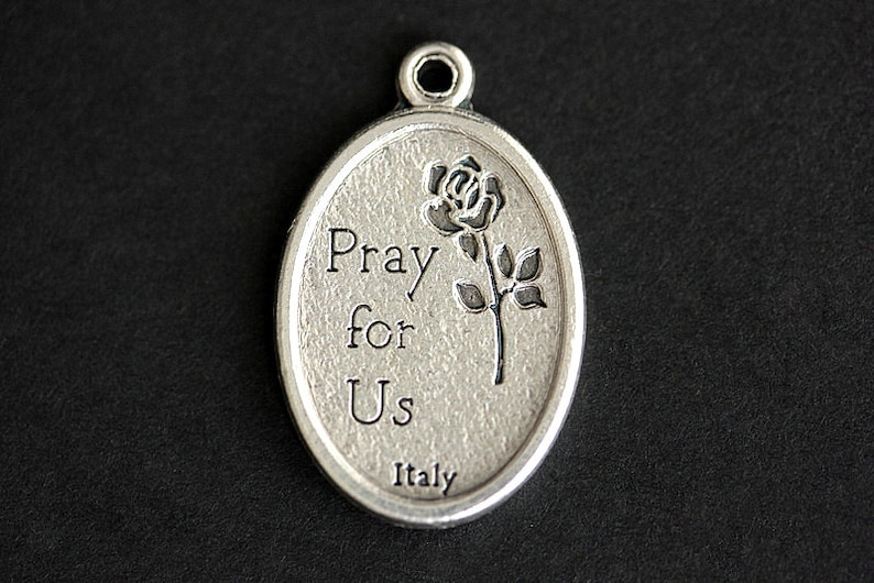 May include: Silver oval pendant with the words "Pray for Us" and a rose design. The pendant is made in Italy.