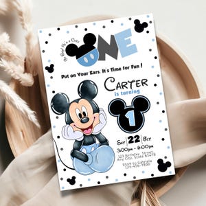 May include: A birthday invitation featuring Mickey Mouse. The invitation is white with black and light blue accents. Text includes "ONE", "Carter is turning", and event details. Mickey Mouse is smiling and wearing blue shorts.