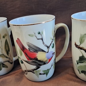 Può includere: Una tazza di ceramica bianca con manico nero e la scritta "But First, Coffee" in grassetto nero. La tazza è posta su uno sfondo sfocato, che suggerisce un'atmosfera accogliente.
