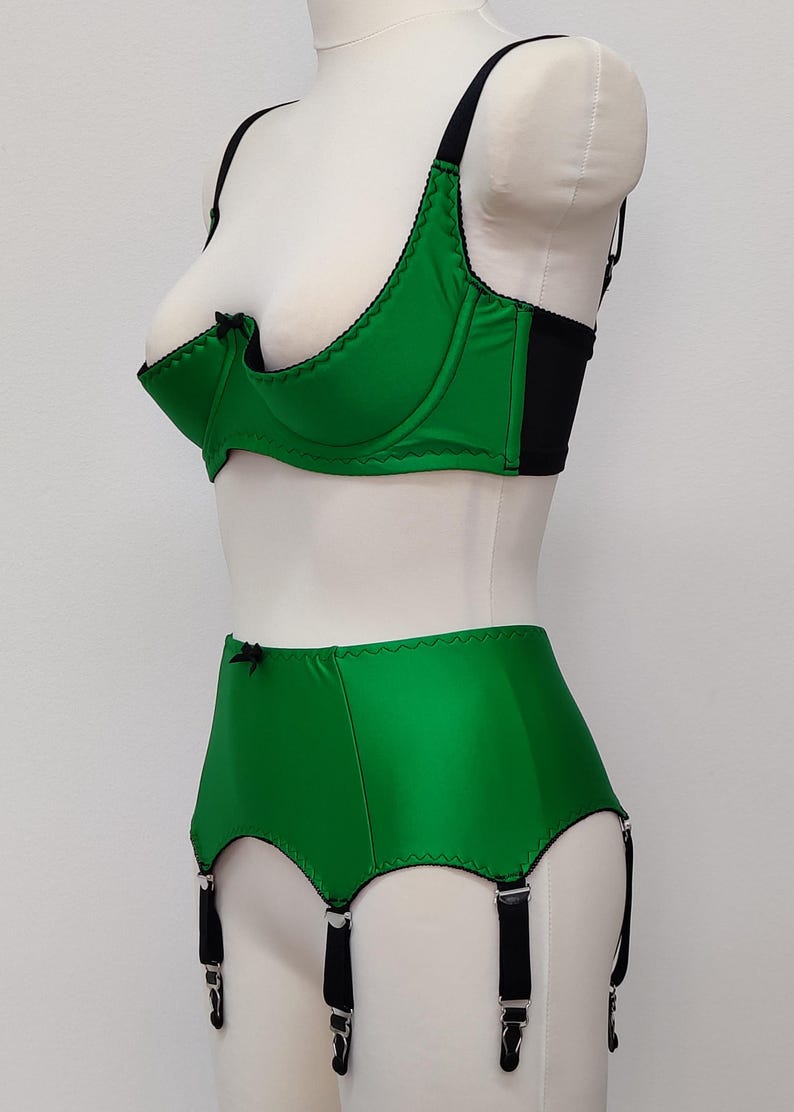 emerald green quarter cup bra with black straps, trim and bow, shown with matching Greta garter belt, side view