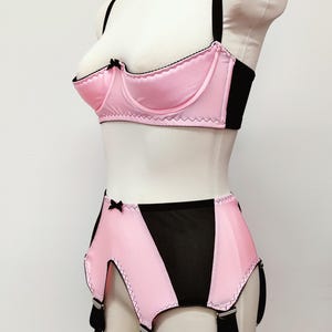 bright pink quarter cup bra with black straps, trim and bow, shown with matching Greta garter belt, side view
