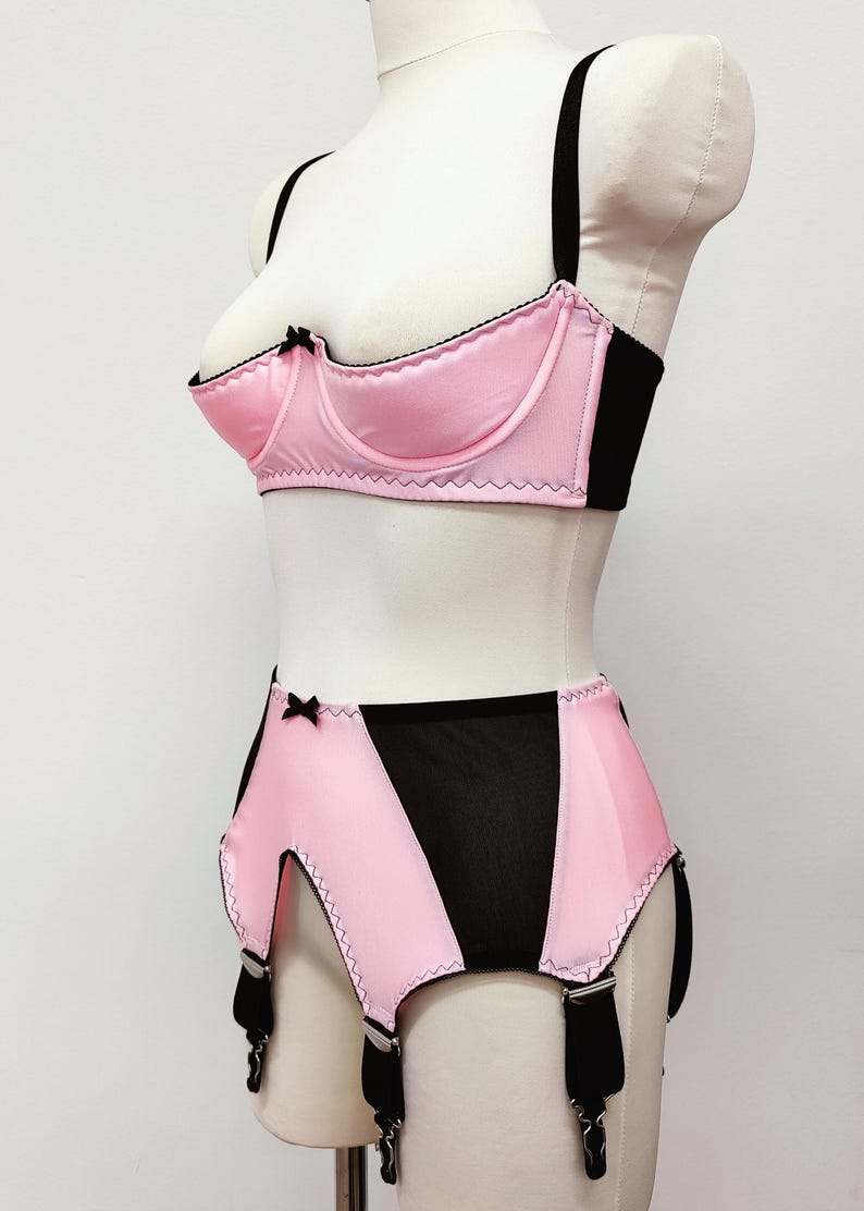 bright pink quarter cup bra with black straps, trim and bow, shown with matching Greta garter belt, side view