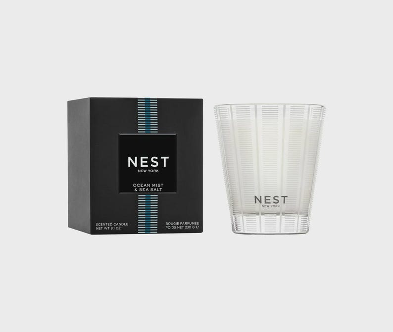 May include: A black and white candle jar with a clear glass lid. The jar has a label that reads "NEST NEW YORK OCEAN MIST & SEA SALT". The candle is a scented candle and is 6.1 ounces.