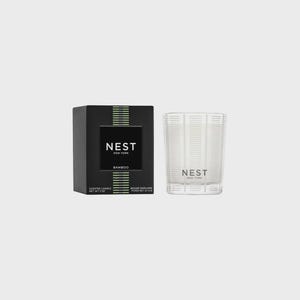 May include: A black and green scented candle with the text "NEST NEW YORK" and "BAMBOO" on the label. The candle is in a clear glass jar with a black lid.