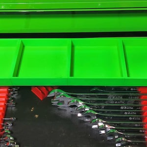 May include: A bright green tool chest with an open drawer revealing a set of wrenches. The wrenches are neatly organized in red holders. The top of the chest has a tray with four compartments.