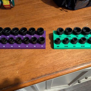 May include: Two sets of black socket wrenches on purple and green holders. The purple holder has sizes from 10 to 24, while the green holder displays sizes from 3/8 to 15/16. The tools are arranged in two rows, with the sizes clearly marked.