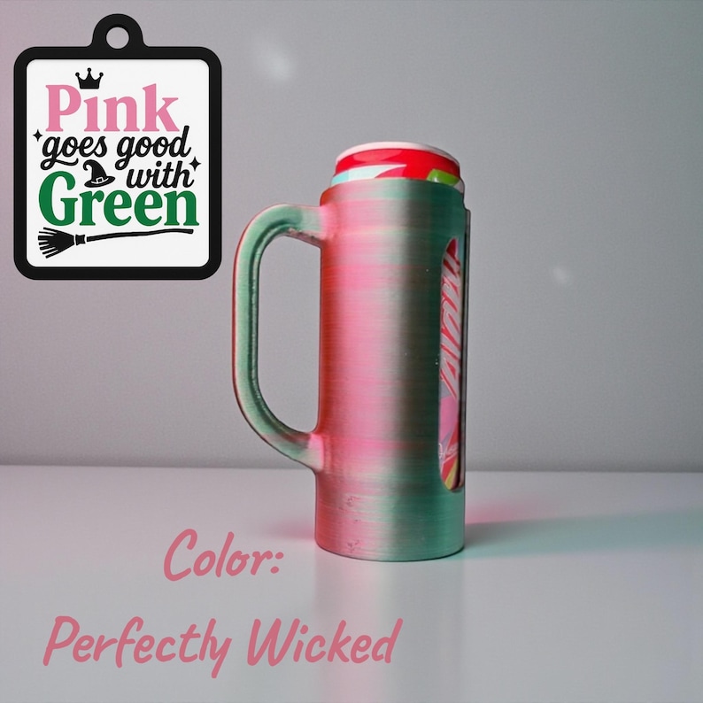 May include: A green and pink mug with a handle, holding a can. The mug has a clear window showing the can's design. A sign with the text "Pink goes good with Green" hangs nearby. The color is "Perfectly Wicked."
