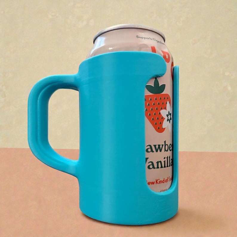 May include: A bright turquoise can holder with a handle, designed to hold a standard-sized beverage can. The holder is made of a solid material and features a curved handle for easy gripping. A can with a strawberry design is visible.