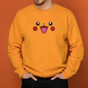 May include: A yellow sweatshirt with a cartoon face of Pikachu, a popular Pokemon character, embroidered on the front.
