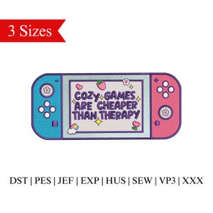 以下が含まれることがあります： ピンクとブルーのニンテンドースイッチの刺繍デザインで、"Cozy Games Are Cheaper Than Therapy"というテキストが書かれています。