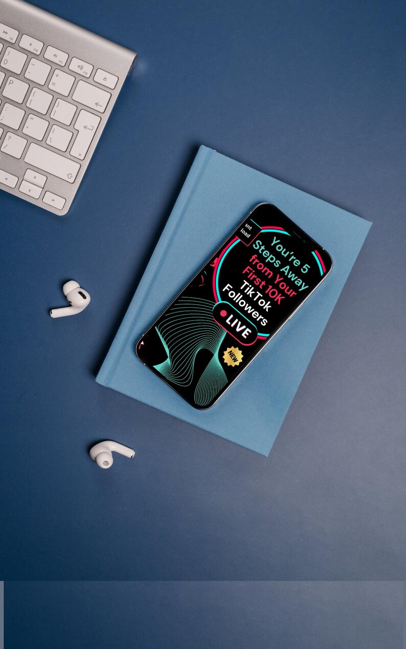 May include: A smartphone with the text "You're 5 Steps Away from Your First 10K TikTok Followers" on the screen, set on a blue book. A silver keyboard and white earbuds are on a blue surface. The phone has a black and teal design.