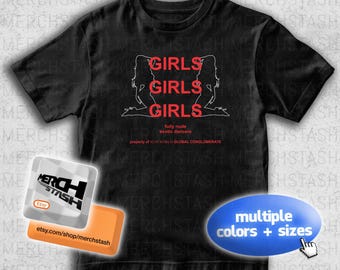 May include: Black t-shirt with the word "GIRLS" repeated three times in red, along with a line drawing of two figures. The text "fully nude exotic dancers" and "property of SLAY WORLD GLOBAL CONGLOMERATE" are also printed on the shirt.