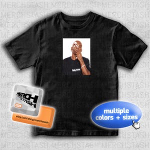 Peut inclure: T-shirt noir avec une image rectangulaire d'une personne fumant. L'image sur le t-shirt porte le mot "Babyfather". Le t-shirt comporte également un graphique "plusieurs couleurs + tailles".