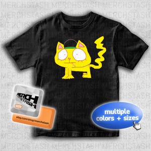 May include: Black t-shirt with a yellow cartoon cat smoking a cigarette, wearing a hat. The cat has large eyes and a zig-zag tail. The shirt has the text "multiple colours + sizes".