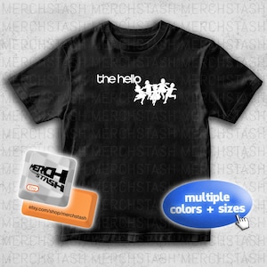 May include: Black t-shirt featuring the text "the hello" and a white graphic of running figures. The image also includes a shop logo and a button that says "multiple colours + sizes".