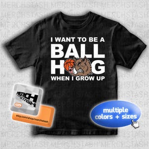 May include: Black t-shirt featuring the phrase "I WANT TO BE A BALL HOG WHEN I GROW UP." The design includes a basketball and a cartoon boar. Available in multiple colours and sizes.