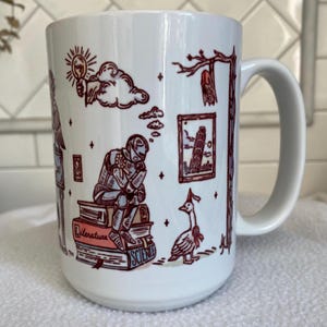 May include: A white ceramic mug featuring a dark red line art illustration of a knight sitting on a stack of books labeled Literature and Science, a goose wearing a party hat, a hanging bat, a framed picture of the Leaning Tower of Pisa, and a lightbulb.