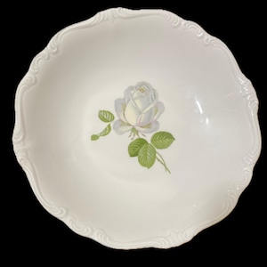 May include: White ceramic serving bowl with a scalloped edge and a floral rose design. The rose is white with a hint of pink and green leaves. The bowl is round and has a decorative edge.