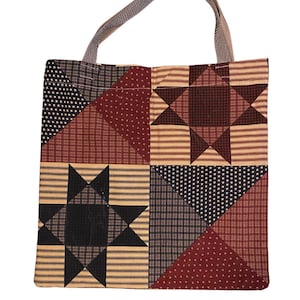 Puede incluir: Un bolso tote de patchwork con un patrón de estrellas repetido. El bolso presenta una variedad de telas en rojo, negro y beige, con un asa gris. El diseño incluye triángulos, cuadrados y formas de estrella, creando una estética rústica.