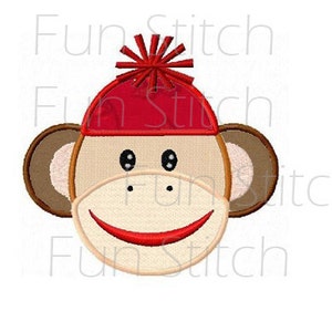 May include: A brown monkey face with a red hat and a white pom-pom. The monkey is smiling with a red mouth.