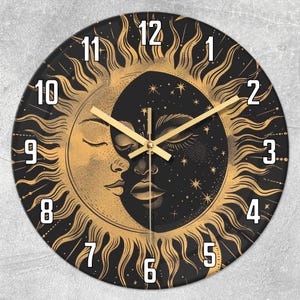 Op de afbeelding: Een ronde wandklok met een hemels ontwerp met een zon- en maanmotief. De klok heeft een zwarte wijzerplaat met gouden details, waaronder de zonnestralen, het gezicht van de maan en de cijfers. De wijzers zijn goudkleurig.