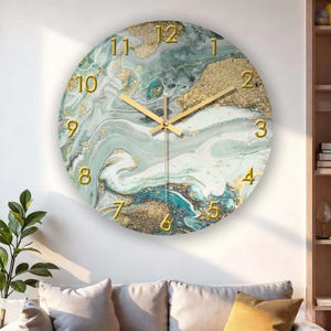 May include: Round wall clock with a marbled design in shades of teal, gold, and white. The clock face features gold numerals and hands. The clock is a decorative item for home decor.