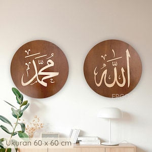 Può includere: Due opere d'arte rotonde da parete in legno. Ogni pezzo è marrone con calligrafia araba bianca. Il pezzo a sinistra dice "Muhammad" e il pezzo a destra dice "Allah". Ogni pezzo misura 60 x 60 cm.