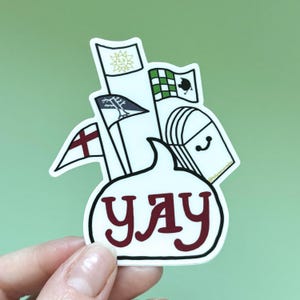 May include: White sticker with a speech bubble that says "yay" in red. The speech bubble is filled with black and white illustrations of flags, a mailbox, and a tree.