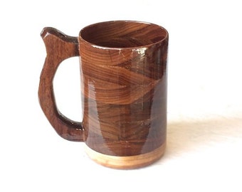 May include: A wooden beer mug with a brown wood grain finish and a natural wood handle. The mug is made of wood and has a smooth, polished finish.
