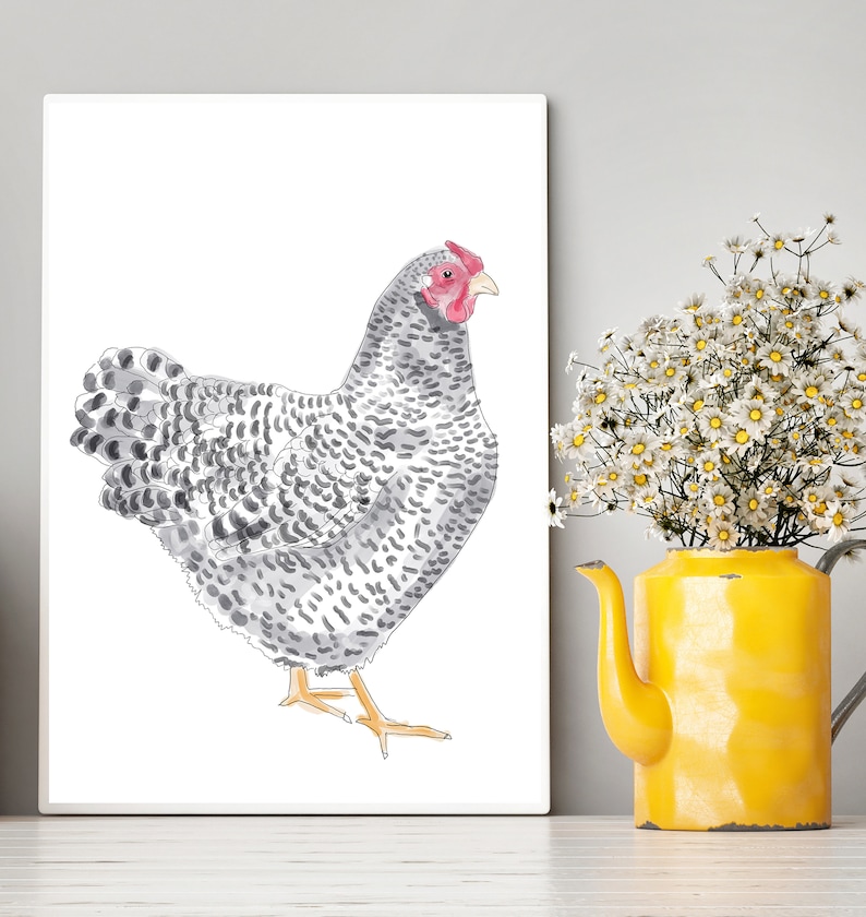 May include: A watercolor print of a chicken with gray and white speckled feathers, a red comb, and yellow feet. The artwork is displayed on a white canvas. A yellow teapot vase holds white flowers, adding a touch of color to the scene.