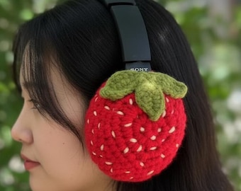 May include: Black headphones with red, crocheted strawberry ear covers. The strawberry design features white seed details and a green crocheted stem and leaves. The headphones have the brand name "SONY" printed on the headband.