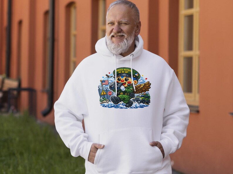 May include: White hooded sweatshirt with a cartoon graphic of a Border Patrol agent. The graphic includes an American flag, a stop sign, and the words "BORDER PATROL" on the agent's hat. The agent is depicted with wings and is wearing a green uniform.