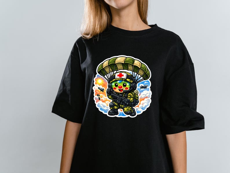 May include: Black t-shirt with a cartoon illustration of a medic soldier parachuting. The soldier wears a helmet with a red cross and holds a weapon. The design includes a parachute, clouds, and a sun. The design is colourful.