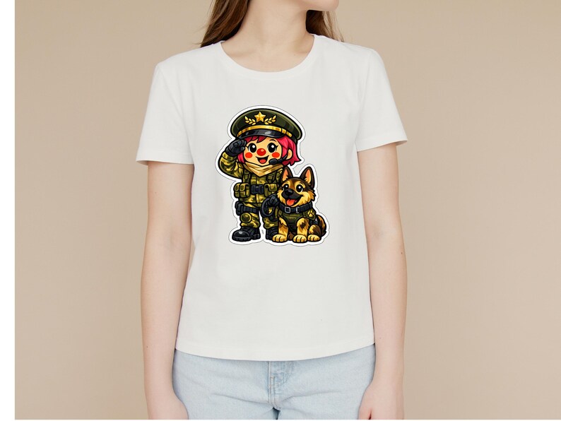 May include: White t-shirt with a cartoon illustration of a soldier saluting, alongside a German Shepherd dog. The soldier is in a green uniform and hat. The dog has a black collar and is sitting. The design is colourful and detailed.