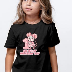 May include: Black t-shirt featuring a pink graphic of a mouse with a bow, the number 1, and the text "SISTER OF BIRTHDAY BOY". The design is in a cartoon style, suitable for a child's birthday celebration.