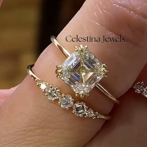 May include: A hand adorned with three gold rings. The main ring showcases a large, square-cut diamond. The other rings are set with smaller diamonds. The text "Celestina Jewels" is visible.