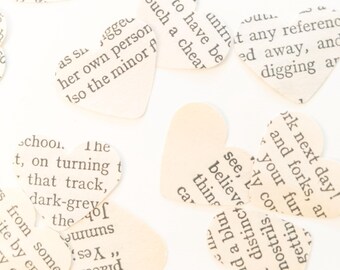 May include: A collection of heart-shaped paper cutouts, each printed with text from a book. The hearts vary in size and are scattered across a white surface, creating a romantic and literary theme.