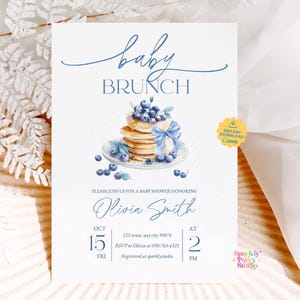 May include: Baby brunch invitation featuring a watercolour illustration of pancakes with blueberries and a blue bow. The invitation includes the text "baby brunch" and baby shower details for Olivia Smith.
