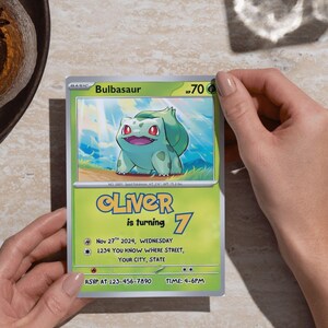 May include: A Bulbasaur-themed birthday invitation card held by hands. The card features a green and yellow design with the name "Oliver" and the number "7". It includes event details like the date, time, and RSVP information.