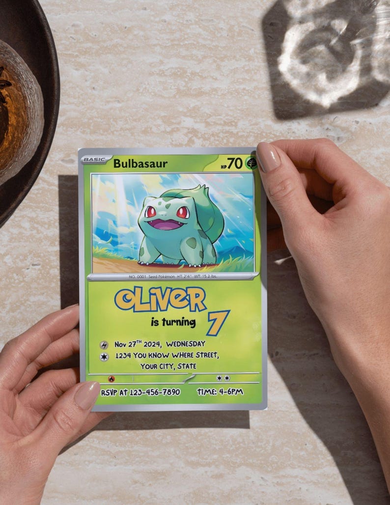 May include: A Bulbasaur-themed birthday invitation card held by hands. The card features a green and yellow design with the name "Oliver" and the number "7". It includes event details like the date, time, and RSVP information.